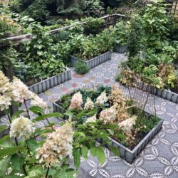 Jardin potager style vegetable garden with mosaic hardscape and hydrangea in the foreground